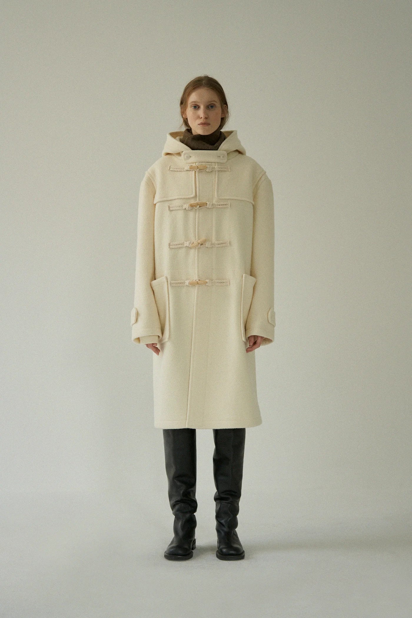 Stay warm and stylish in the hand-crafted Hooded Duffle Coat. Made with premium boucle fabric, this oversized coat features toggle-and-cord closures and a functional hood with a protective neck visor. Fully lined for comfort and warmth, its artisanal details and thoughtful pockets make a statement of sophistication.