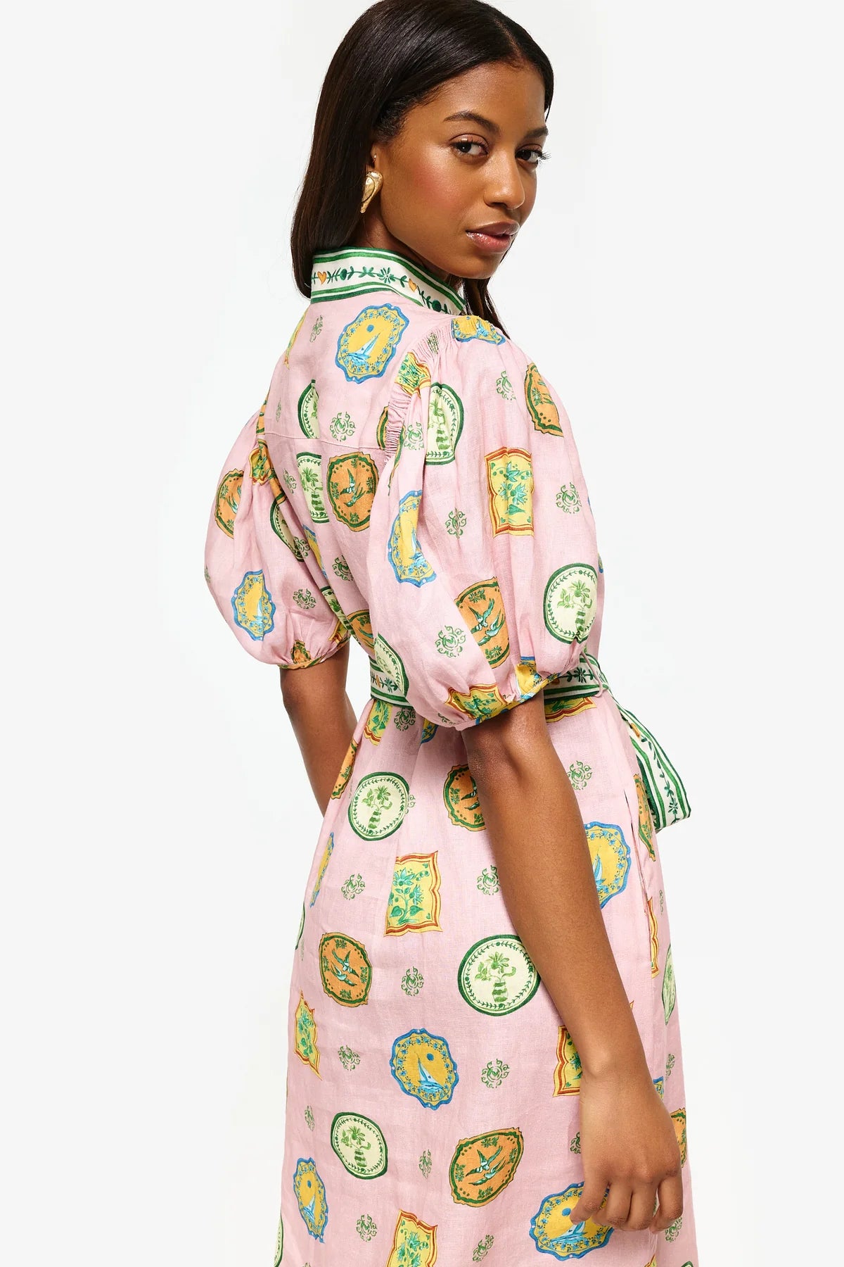 Get ready to turn heads at your next summer dinner party with the Porcelain Shirtdress! This delightful pink midi features charming green and yellow accents and a fitted silhouette with elasticated balloon sleeves. The elegant shell buttons, in-seam pockets, and self-tie belt add practicality and playful details. Elevate your summer style with the Porcelain Shirtdress.