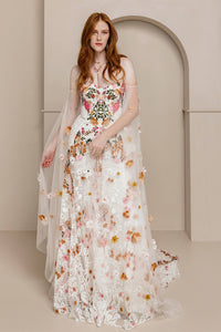 Introducing Meadow Gown - a work of art inspired by desert blooms. Its vibrant florals are delicately embroidered on sand-dyed tulle, creating a stunning contrast against bare terrain. With a fully boned bodice for support and a dramatic train with cascading flowers, this gown exudes a playful yet sophisticated charm. Perfect for the bold bride looking to infuse color into her special day.