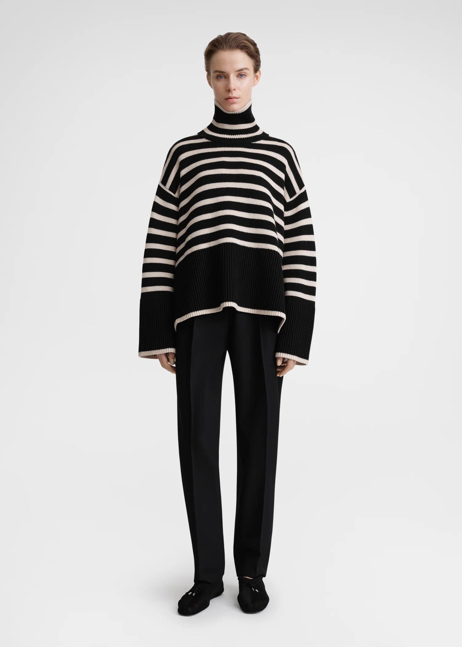 Unleash your fashion-forward style with the Striped Wool Jersey by Toteme. Crafted from heavyweight wool and organic cotton, this turtleneck sweater boasts a striking sand and black striped pattern. Certified by the Responsible Wool Standard, its boxy silhouette, tall neck, and extra-long sleeves with dropped shoulders exude luxury and sophistication. Leave the neck undone for an effortlessly chic look.