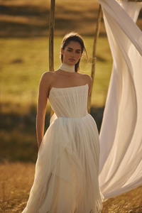 Elevate your wedding day look with the Klelia Gown. Its soft netting, Georgian-style corsetry, and delicate tucks exude both romance and structure. Contemporary style meets timeless charm in the ballgown silhouette, while modern design sensibilities add a touch of uniqueness. Make a statement on your special day with this reimagined classic.