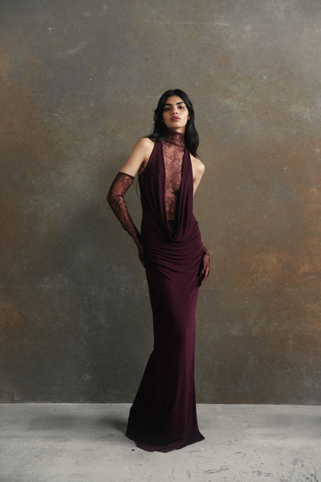 Indulge in the opulence of the Amaryllis Maxi Dress. This full length dress features a high neck and a draped cowl neck for a touch of sophistication. The fitted lace bodice and included gloves add an extra level of elegance to this luxurious piece.