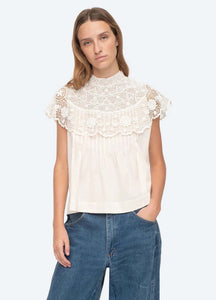 Be a vision of delicate beauty in the Serita Top by Sea New York. This cream-colored top boasts a crochet lace cape and intricate stitched pleat detailing, creating a whimsical and feminine look. The perfect addition to any wardrobe for adding a touch of elegance and charm.