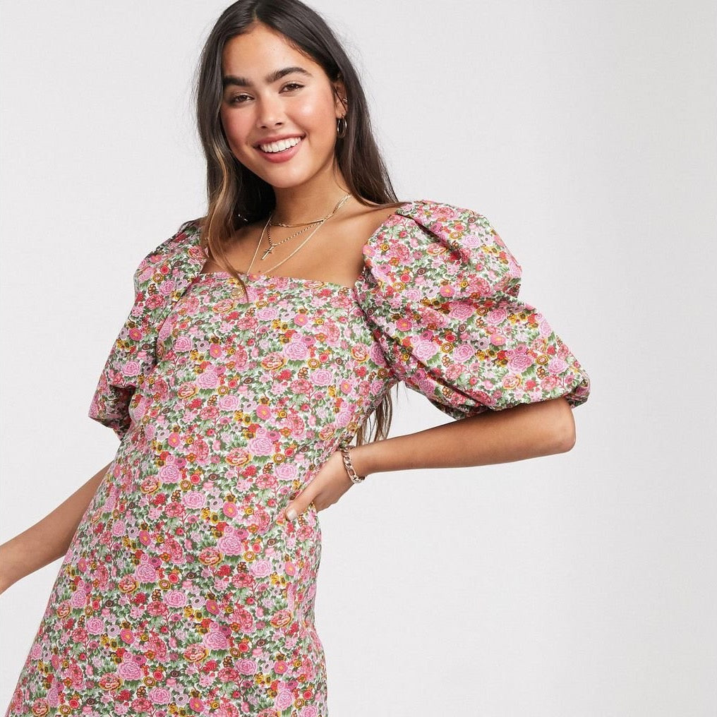 Introducing the Robe Tegwen, a vintage-inspired dress for the modern woman. Featuring a floral print and puffy sleeves, this short dress is perfect for any casual occasion. With its square neckline, it exudes an effortless yet chic style. Get yours now and stand out with this unique and stylish piece.