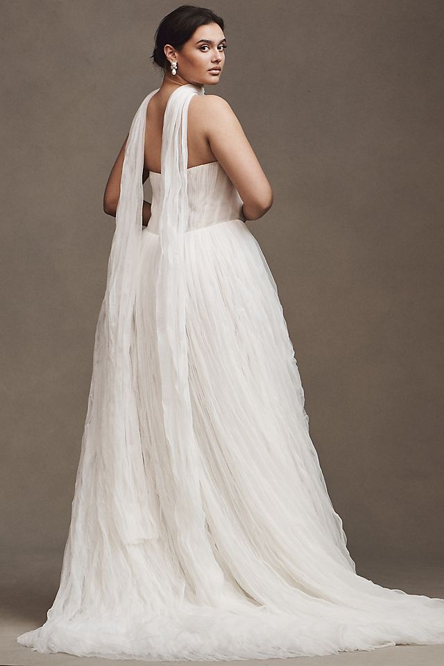 Elevate your wedding day look with the Klelia Gown. Its soft netting, Georgian-style corsetry, and delicate tucks exude both romance and structure. Contemporary style meets timeless charm in the ballgown silhouette, while modern design sensibilities add a touch of uniqueness. Make a statement on your special day with this reimagined classic.