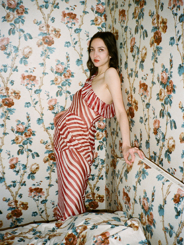 Indulge in the timeless charm of Theodora Maxi Dress. Its one-shouldered design and silk candy stripes evoke a sense of theatrical elegance. Panelled seams create an abstract stripe pattern in cream and deep red hues. Cinch the waist for added allure and pair with a dark lip and pointed heels for a touch of old-school Parisian chic.