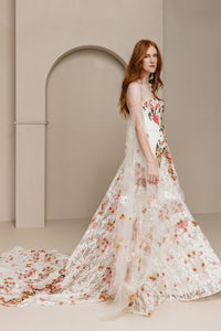 Introducing Meadow Gown - a work of art inspired by desert blooms. Its vibrant florals are delicately embroidered on sand-dyed tulle, creating a stunning contrast against bare terrain. With a fully boned bodice for support and a dramatic train with cascading flowers, this gown exudes a playful yet sophisticated charm. Perfect for the bold bride looking to infuse color into her special day.