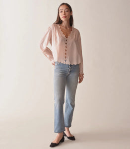 Introducing the Elayne Top from Doen, made from the softest organic cotton voile. This fan-favorite style features a plunging V-neck, double scallop sleeves, and an adjustable back waist tie for the perfect fit. Playful cutouts and mother-of-pearl buttons add a touch of whimsy, while pintucks create texture and dimension. Look and feel effortlessly beautiful in this must-have top.