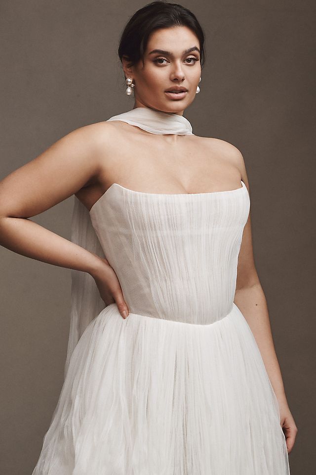 Elevate your wedding day look with the Klelia Gown. Its soft netting, Georgian-style corsetry, and delicate tucks exude both romance and structure. Contemporary style meets timeless charm in the ballgown silhouette, while modern design sensibilities add a touch of uniqueness. Make a statement on your special day with this reimagined classic.