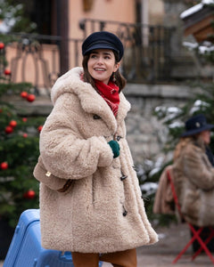 Introducing the must-have Faux-fur Hooded Coat by Marant Étoile. Crafted with a soft faux-fur exterior, this coat combines luxury and comfort. The classic hood and front toggle fastening add a timeless touch to the piece. With its beige hue and functional side pockets, it's a practical and stylish addition to any wardrobe. Worn by Emily in Paris.