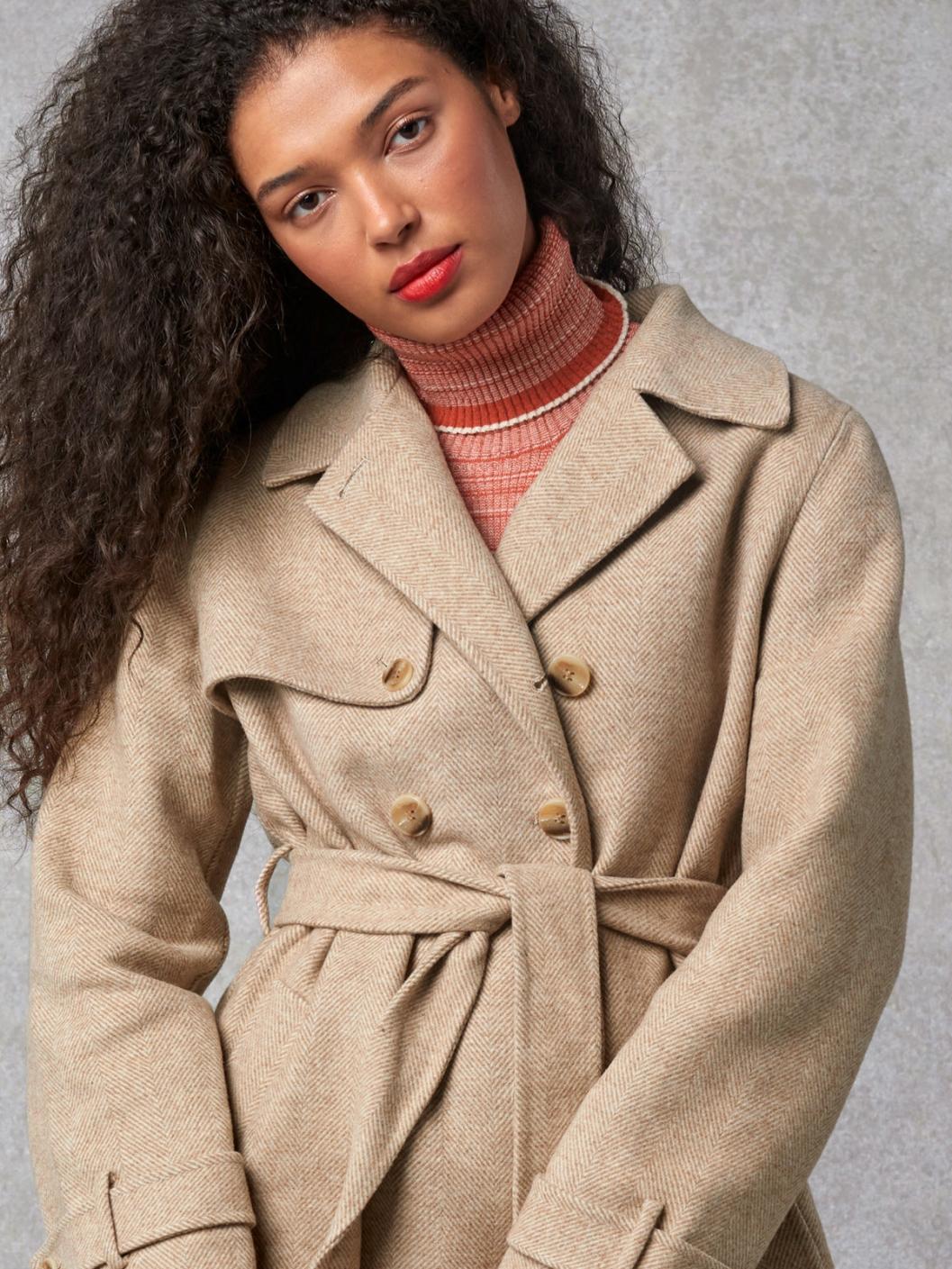 Indulge in luxury with the Manteaux Elisa. This long coat with a classic beige herringbone pattern and a belted waist exudes elegance. The cross-over collar, button details on the cuffs, and back slit add sophistication. Elevate your style with this statement piece.