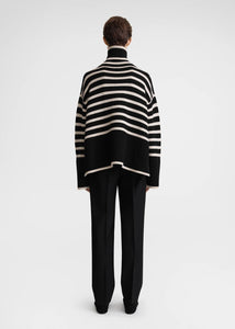 Unleash your fashion-forward style with the Striped Wool Jersey by Toteme. Crafted from heavyweight wool and organic cotton, this turtleneck sweater boasts a striking sand and black striped pattern. Certified by the Responsible Wool Standard, its boxy silhouette, tall neck, and extra-long sleeves with dropped shoulders exude luxury and sophistication. Leave the neck undone for an effortlessly chic look.