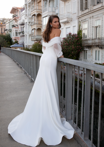 Experience pure elegance with Robe Alora! This bohemian-inspired wedding dress features a sexy satin mermaid silhouette, long lace sleeves, and sultry off-the-shoulder detailing for a ravishing and timeless look. Get ready to turn heads on your special day!