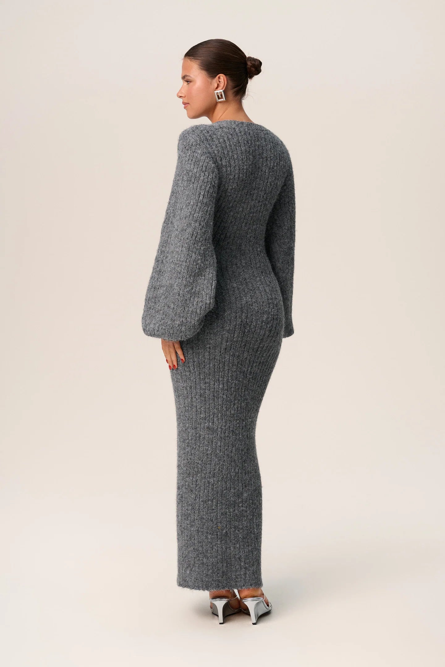 Embrace luxury with the Silana Knit Dress. This maxi dress in grey melange is made from a cozy wool-blended fabric for both style and warmth. Boasting an hourglass fit, front button-up closure, and elegant V-neck collar, this dress exudes sophistication. Complete with full-length balloon sleeves and distinctive cuffs, elevate your style with this exclusive piece.