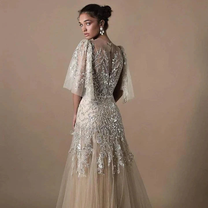 Crafted with expert precision, the Fleurie Gown is the perfect dress for any special occasion. The jewel neckline and bell sleeves add elegant touches while the fitted bodice and trumpet silhouette accentuate your curves. With a back keyhole and sweep train, this embroidered dress exudes sophistication.