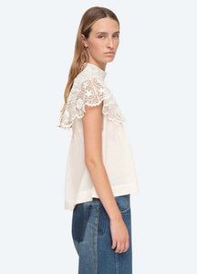 Be a vision of delicate beauty in the Serita Top by Sea New York. This cream-colored top boasts a crochet lace cape and intricate stitched pleat detailing, creating a whimsical and feminine look. The perfect addition to any wardrobe for adding a touch of elegance and charm.