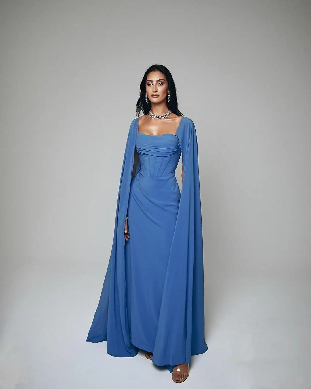 Elevate your style with Dress Rosine. Its square neckline and elegant design create a flattering silhouette. The floor length hem and ruffle details add a touch of elegance. And with a court train and zipper closure, it's the perfect choice for any formal occasion. Make a statement in blue.