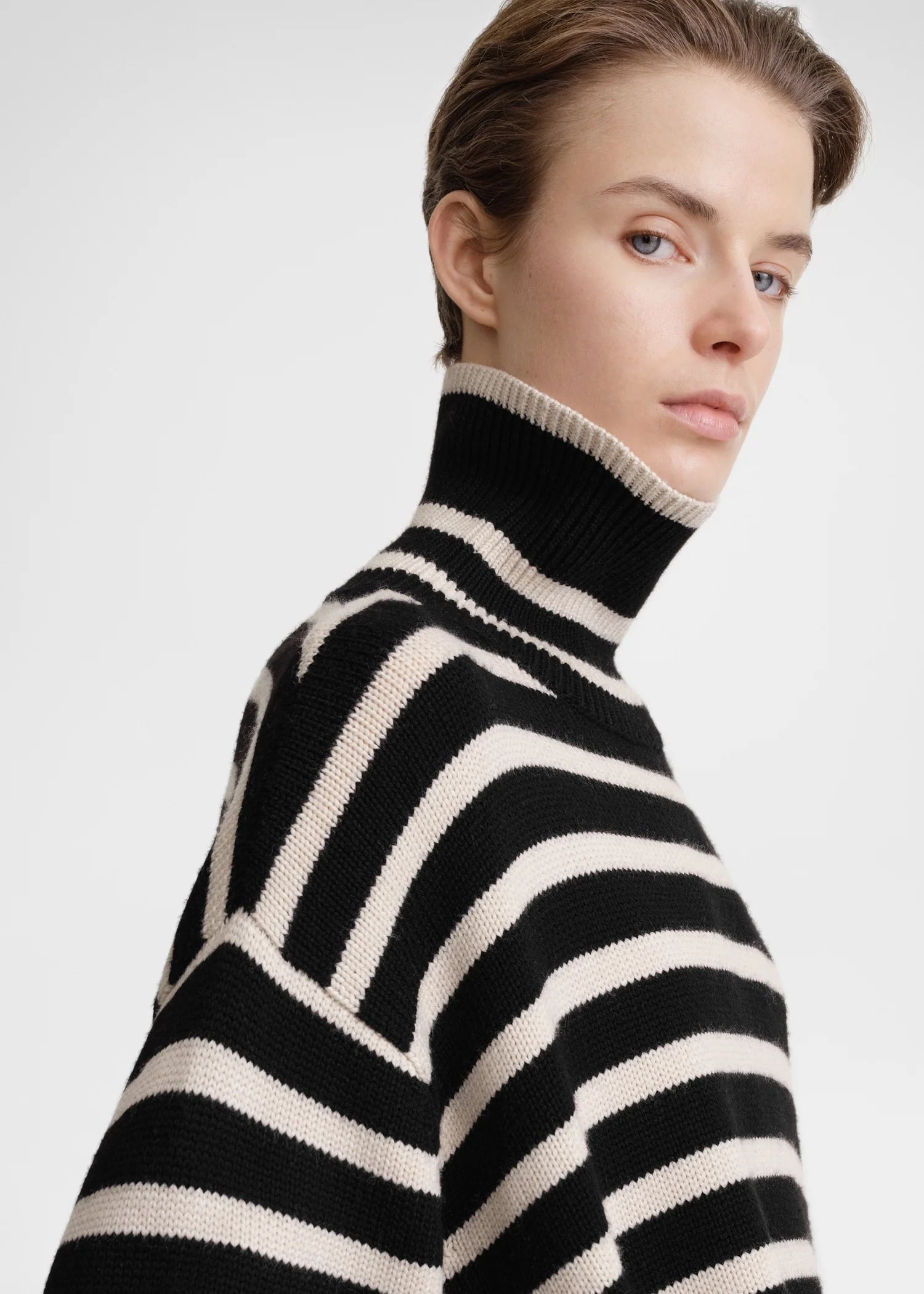 Unleash your fashion-forward style with the Striped Wool Jersey by Toteme. Crafted from heavyweight wool and organic cotton, this turtleneck sweater boasts a striking sand and black striped pattern. Certified by the Responsible Wool Standard, its boxy silhouette, tall neck, and extra-long sleeves with dropped shoulders exude luxury and sophistication. Leave the neck undone for an effortlessly chic look.