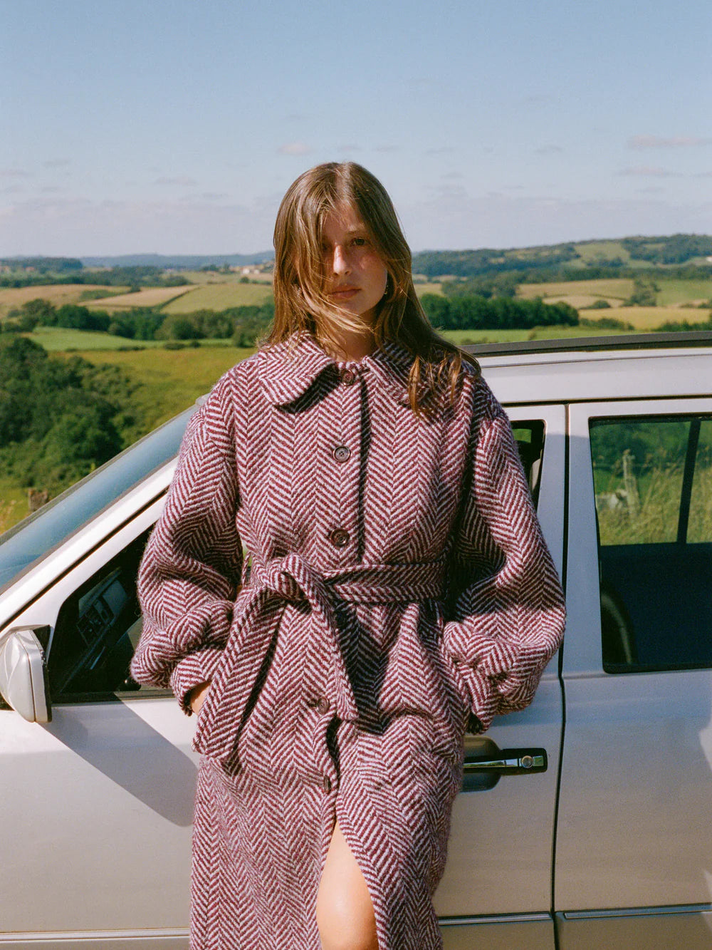 The Manteau Gerard is a long wool coat with a chevron pattern in deep burgundy. Its cinched waist adds a flattering touch, while the warm and durable wool material will keep you stylish and cozy all winter long. Elevate your cold-weather wardrobe with this luxurious and timeless piece.