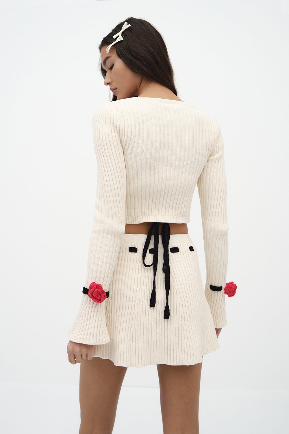 Indulge in luxury with the Roxana Cardigan by For Love & Lemons. Made of a midweight chenille ribbed knit fabric, this cropped cardigan features a round neck and front snap button closure adorned with delicate rosette appliques. The long sleeves and removable chenille rosette on the cuffs add a touch of elegance to this unlined piece. Available in a timeless white color, this cardigan is perfect for adding a touch of sophistication to any outfit.