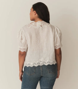 Crafted from lightweight, crisp ramie, the Idella Top from Doen features a plunging V-neckline, short puffed sleeves, and intricate embroidered lace details. Mother-of-pearl buttons adorn the front, while lace insets add delicate touches. This antique-inspired top is perfect for a breezy, feminine look.