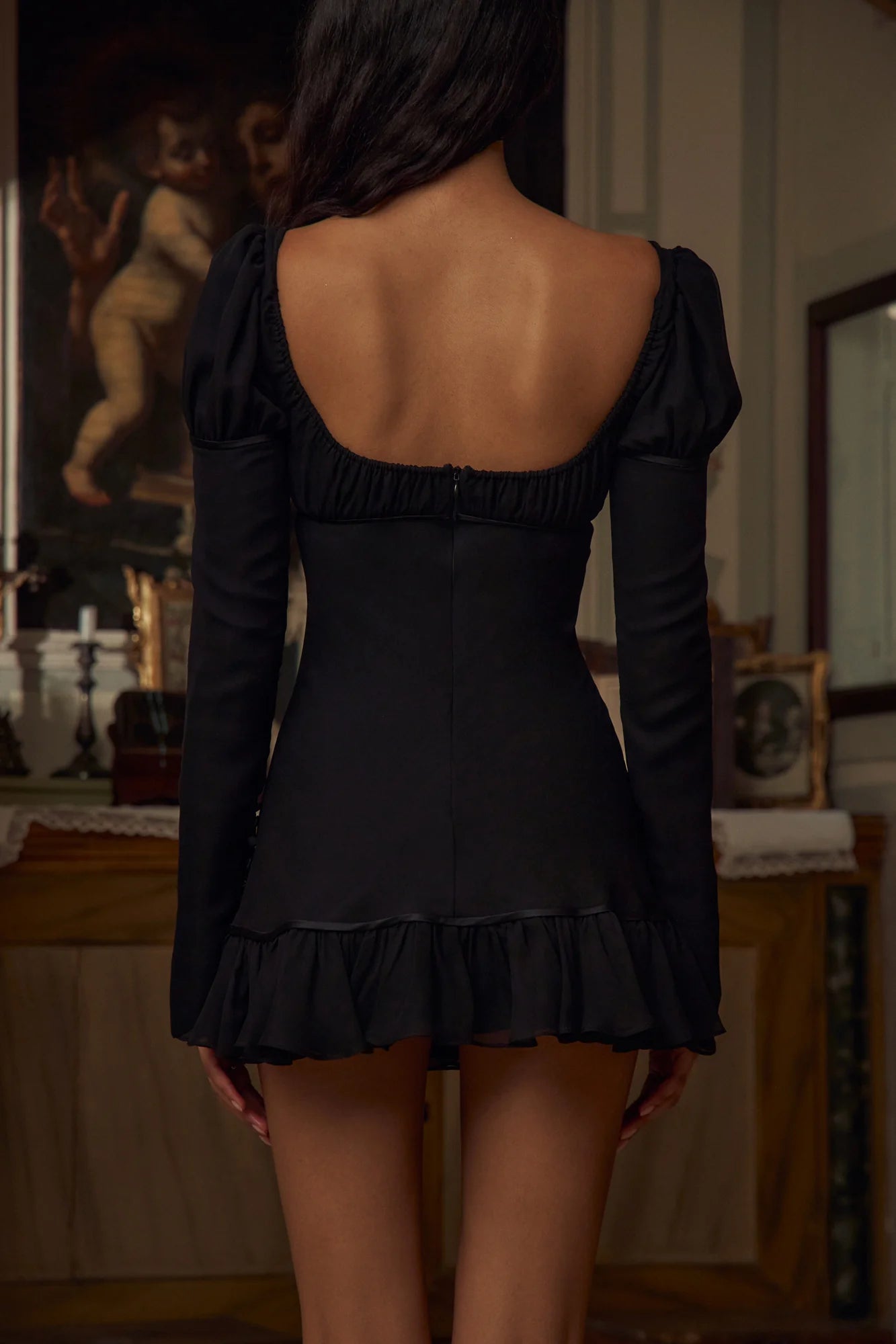 Indulge in luxury and elegance with the Verona Mini Dress in Noir. With shirring on the bust, sleeves, and ruffle hem, this dress flatters your figure in style. Its adjustable neckline and functional sleeve buttons add sophistication. Embrace the adventure and elevate your style with this exclusive piece!