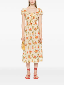 The Clarinet Floral-Print Midi Dress by Doen features a pale yellow floral print, a square neck, and short puff sleeves with elasticated cuffs. The smocked waist and bow detail at the front create a flattering silhouette. Perfect for adding a touch of spring to your wardrobe.