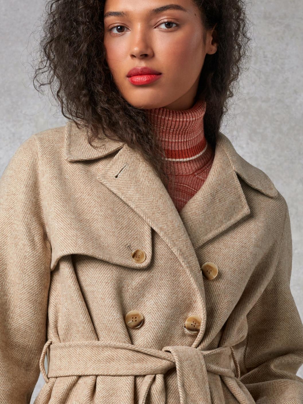 Indulge in luxury with the Manteaux Elisa. This long coat with a classic beige herringbone pattern and a belted waist exudes elegance. The cross-over collar, button details on the cuffs, and back slit add sophistication. Elevate your style with this statement piece.