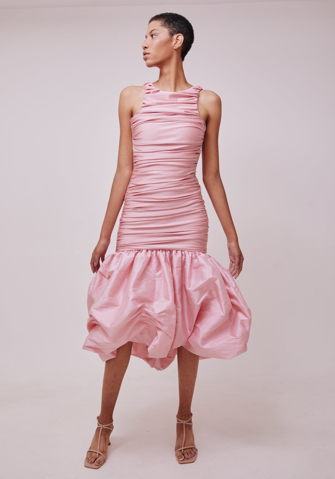 The Bahia Dress is perfect for any occasion with its beautifully crafted sleeveless design and light pink bundage satin material. Its mermaid silhouette will flatter any figure, and the open back adds a touch of elegance. The cascading folds and maxi length make this dress a timeless choice for any woman's wardrobe.