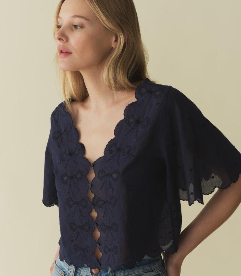 The Kacy Top by DOEN blends vintage charm with modern elegance. Crafted in 100% organic cotton voile, this blouse features charming cutouts, delicate bow embroidery, and breezy elbow-length sleeves. With scalloped details and delicate dot embroidery, this top is a playful yet sophisticated addition to your wardrobe.