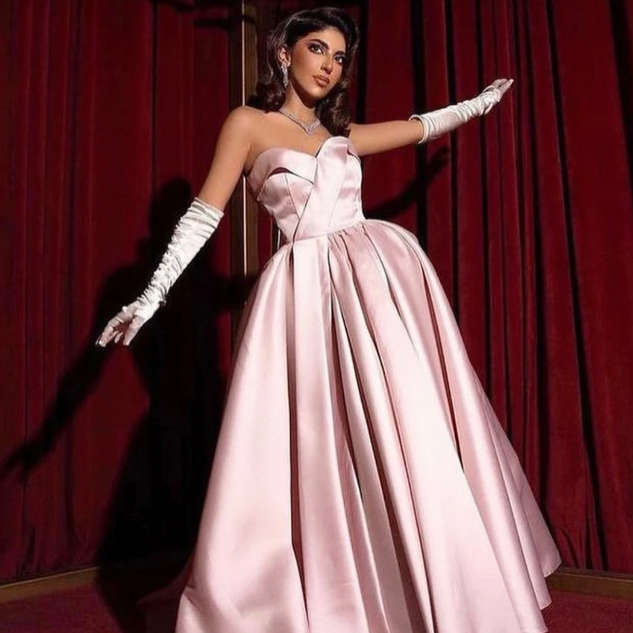 Unleash your daring side with the Robe Amena. This evening dress boasts vintage elegance with ruffled details and a strapless A-line design. Its pink hue adds a simple touch while the gloves add a bold statement. Perfect for formal occasions and prom, this dress will make you stand out in any party.