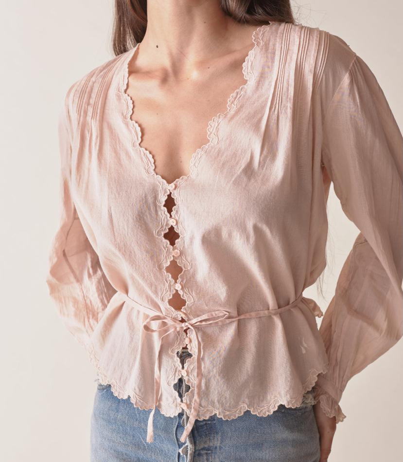 Introducing the Elayne Top from Doen, made from the softest organic cotton voile. This fan-favorite style features a plunging V-neck, double scallop sleeves, and an adjustable back waist tie for the perfect fit. Playful cutouts and mother-of-pearl buttons add a touch of whimsy, while pintucks create texture and dimension. Look and feel effortlessly beautiful in this must-have top.