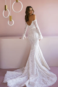 Indulge in the timeless elegance of the Robe Jeane. This strapless column showcases bare shoulders and long sleeves, adorned with delicate applique flowers. The exquisite lace flows into a dazzling train, while a white silk ribbon cinches the waist. Experience luxury with beaded accents and a delicate row of buttons down the back.