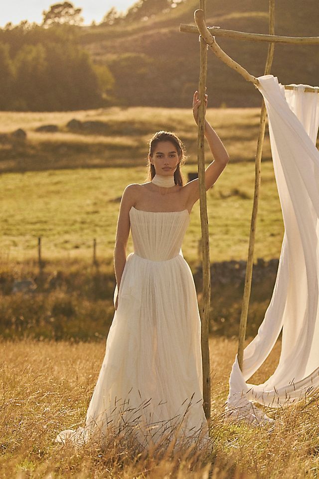 Elevate your wedding day look with the Klelia Gown. Its soft netting, Georgian-style corsetry, and delicate tucks exude both romance and structure. Contemporary style meets timeless charm in the ballgown silhouette, while modern design sensibilities add a touch of uniqueness. Make a statement on your special day with this reimagined classic.