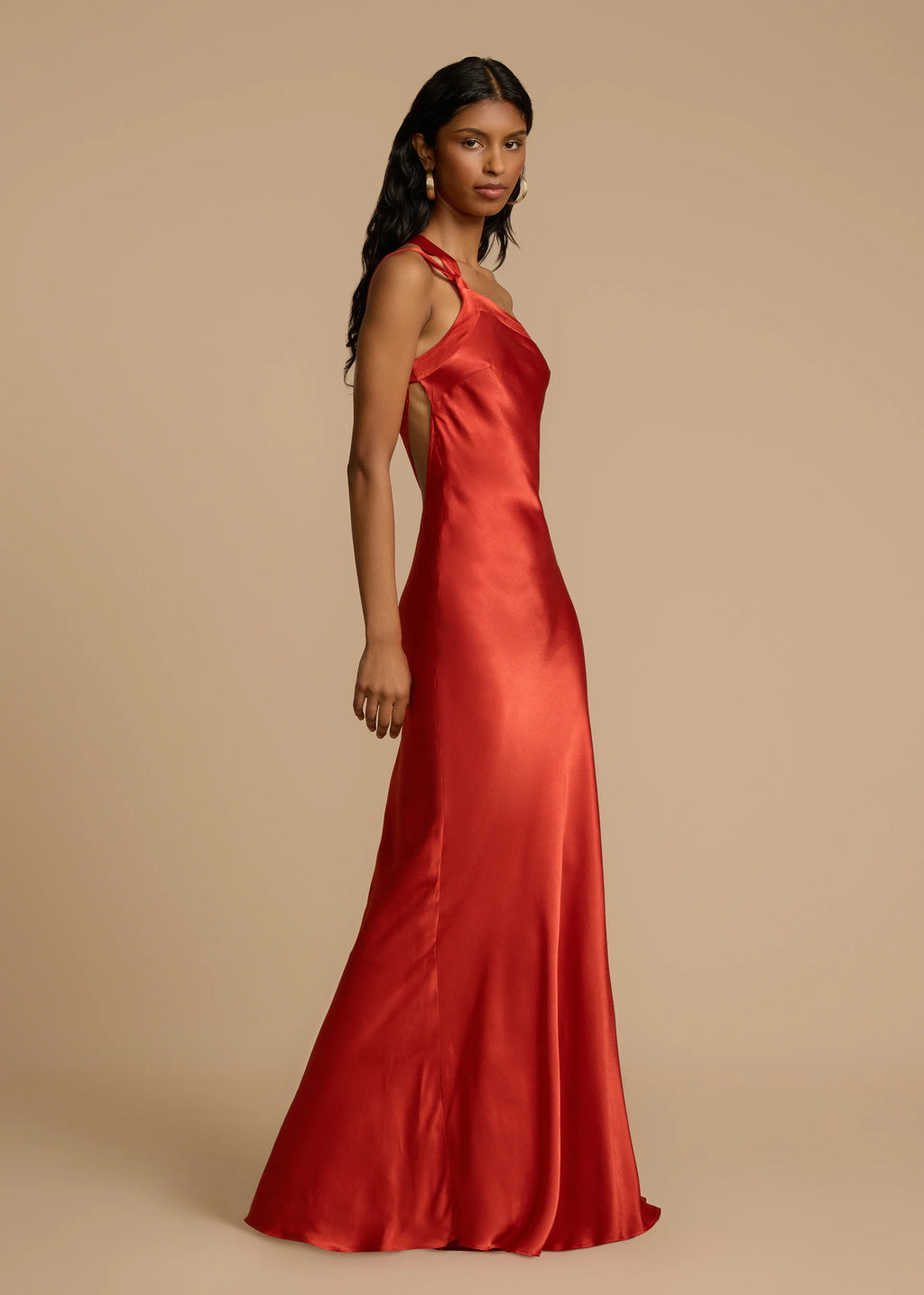 Intensify your allure with the Monique Dress by Arcina Ori. In stunning rust red, cut on the bias for a flattering fit, its one-shoulder design and open back will turn heads. This floor-length gown showcases crossover detailing and a graceful strap, sculpted to embrace your curves and awaken the senses.