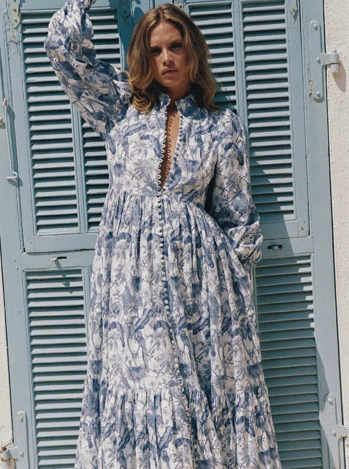 Be the center of attention at your next event with our Royal Flush Dress. Made from 100% Linen Scallop, this maxi dress features a unique Jungle Blue print, functional buttons, and blouson sleeves with elasticated cuffs. Complete the look with the included eyelet belt. Expertly crafted for a statement-making look.