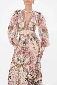 Upgrade your wardrobe with the elegant Bambino Bliss Silk Dress. Made with a vintage pink flower pattern and luxurious silk print, this dress exudes sophistication. The deep V neck and lantern sleeves add a touch of glamour while the gold buttons give it a classic touch. Perfect for any formal occasion.