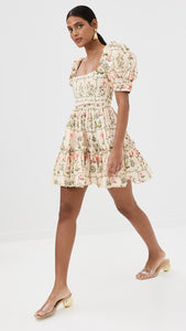 The Alaria Oasis Dress from Agua by Agua Bendita is a stunning piece that combines lightweight, non-stretch poplin fabric with a beautiful floral print. The tiered ruffles add elegant movement, while the wired seams at the bodice provide a flattering fit. Featuring a square neckline and short puff sleeves with banded cuffs and bead embellishments, this dress is a must-have for any special occasion. Securely fastened with a hook-and-eye and hidden zip at the back.