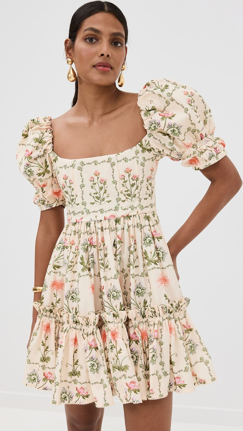 The Alaria Oasis Dress from Agua by Agua Bendita is a stunning piece that combines lightweight, non-stretch poplin fabric with a beautiful floral print. The tiered ruffles add elegant movement, while the wired seams at the bodice provide a flattering fit. Featuring a square neckline and short puff sleeves with banded cuffs and bead embellishments, this dress is a must-have for any special occasion. Securely fastened with a hook-and-eye and hidden zip at the back.