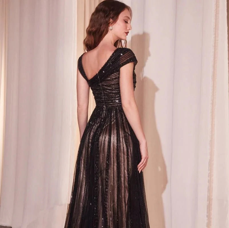 Indulge in elegance with our Chiara Gown, designed for the daring and bold. Featuring an off-the-shoulder asymmetrical bodice with dazzling horizontal beading, and a layered tulle skirt adorned with a vertical beaded motif, this dress exudes modern glamour. Whether it's a gala or special evening, make a statement in this captivating and timeless piece.