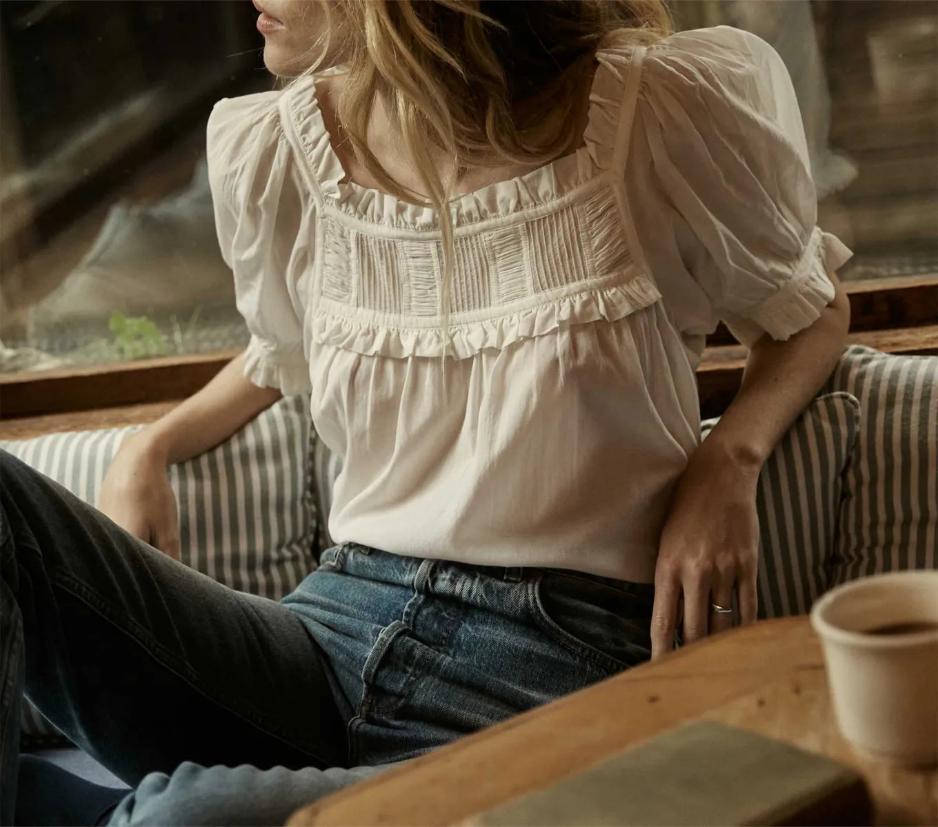 The Frances Top by Dôen is perfect for warm days, featuring short puff sleeves and a relaxed fit. It boasts a square neck yoke with a delicate lace ruffle and alternating panels of lace and shirring. In a Salt color with cream lace, this top offers a charming and modern look inspired by past decades.