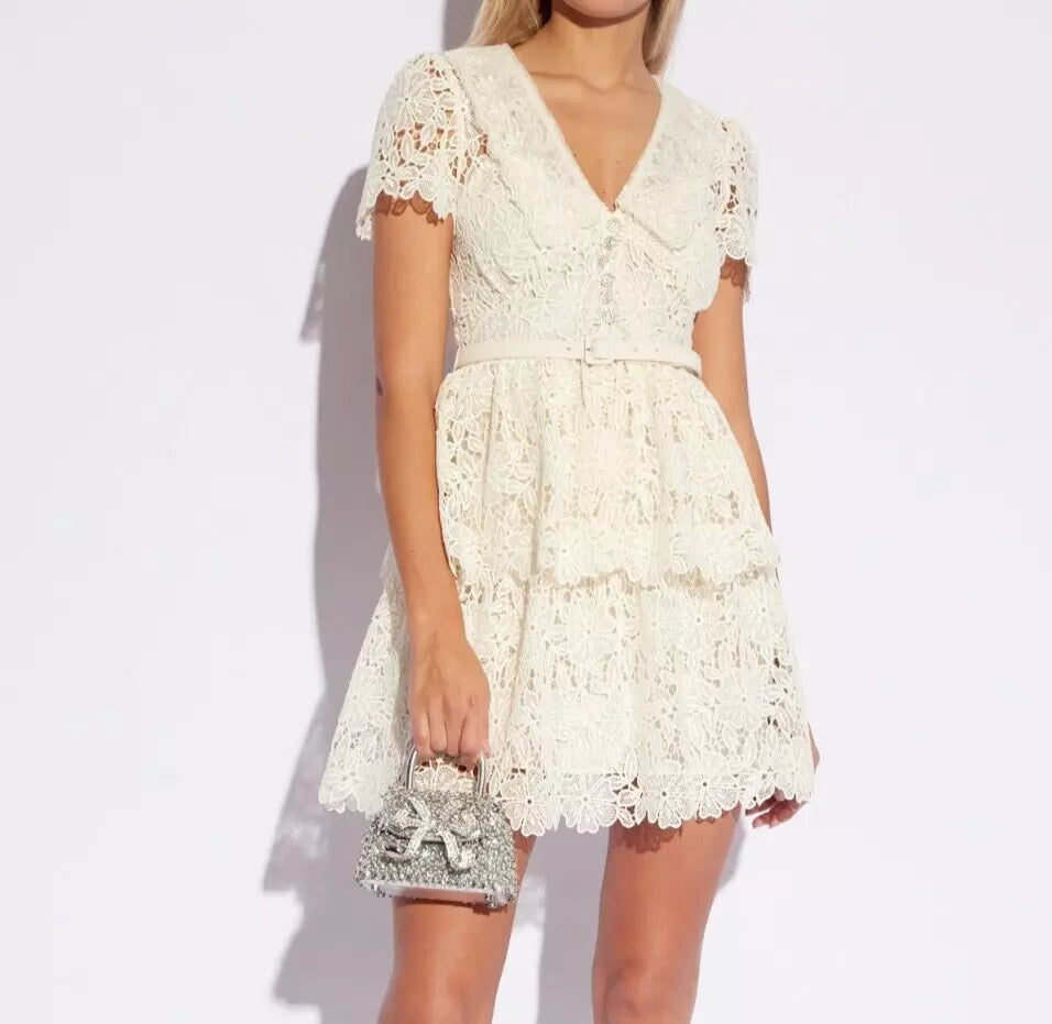 Introducing Flower Lace Mini Dress by Self-Portrait - a reimagined classic for the modern woman. Embodying a signature sensuality and ease, this elegant dress features delicate lace embroidery, feminine short sleeves, and a flattering v-neck. Complete with a sash for added style, it's perfect for any summer occasion.