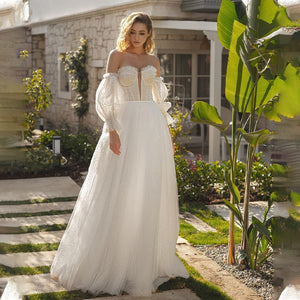 Get ready to turn heads in the Robe Alara! With its off-shoulder, sweetheart neckline and A-line silhouette, this bohemian wedding dress is both chic and comfortable. The delicate lace and long sleeves add an extra touch of romance, while the buttons down the back and floor-length skirt create a stunning finishing touch. Say yes to style and comfort on your special day!