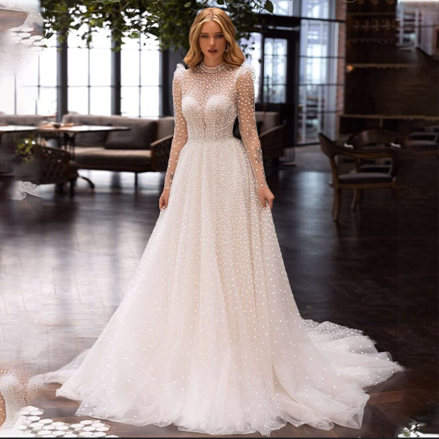 Indulge in the luxurious and bohemian style of Robe Matilda. With its long sleeves, high neck, and floor-length tulle, this wedding gown effortlessly exudes sophistication. Walk down the aisle with elegance and grace in this ethereal masterpiece.