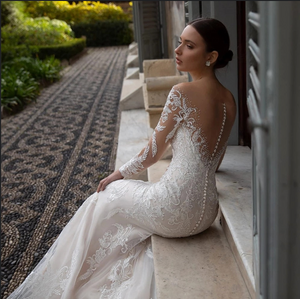 Indulge in the luxury of the Robe Neila. With its elegant lace design, this bridal gown exudes sophistication and chic style. The open back and siren mermaid silhouette add a sexy touch, making you feel like a true siren on your special day. Elevate your bridal look with this exclusive piece.