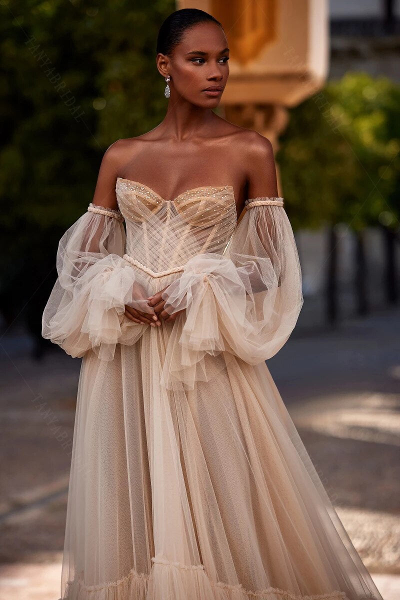 Introducing the luxurious and exclusive Robe Bay, a bohemian-inspired champagne wedding dress with layers of tulle and detachable sleeves. This elegant gown exudes simplicity and charm, perfect for a chic and sophisticated bride. Experience the ultimate in bridal fashion with Robe Bay.