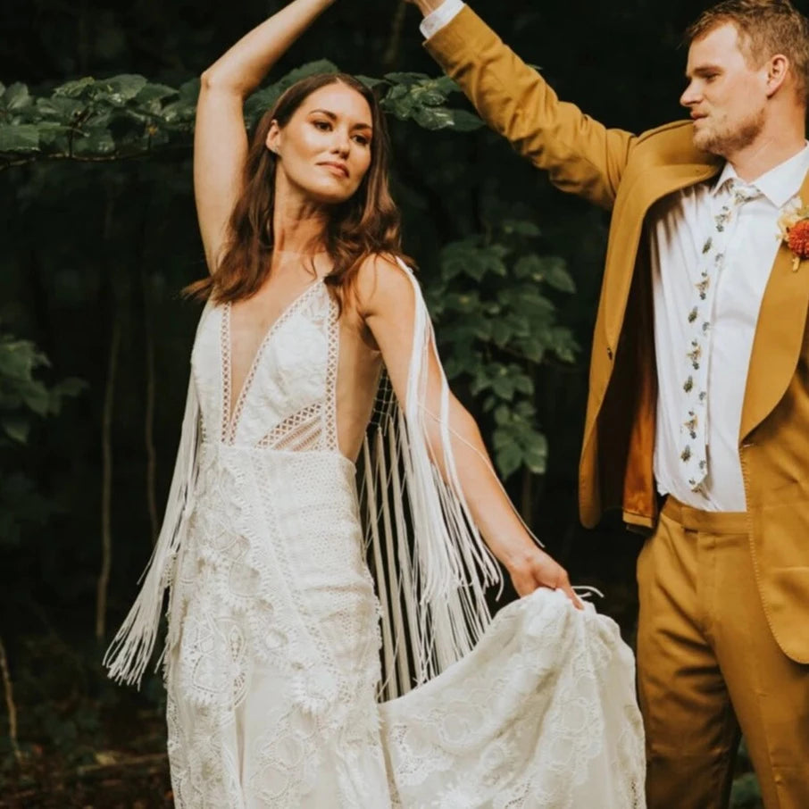 Experience pure elegance and bohemian charm with the Robe Posey. This unique wedding dress features ethereal tassel fringe and a deep V-neck, perfectly embodying the typical style of Rue. Feel like a true boho bride in this beautifully crafted bridal gown.