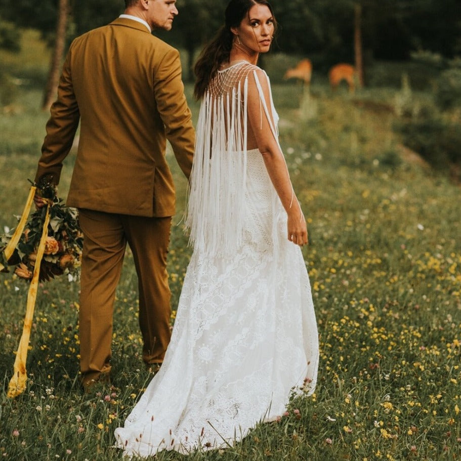 Experience pure elegance and bohemian charm with the Robe Posey. This unique wedding dress features ethereal tassel fringe and a deep V-neck, perfectly embodying the typical style of Rue. Feel like a true boho bride in this beautifully crafted bridal gown.