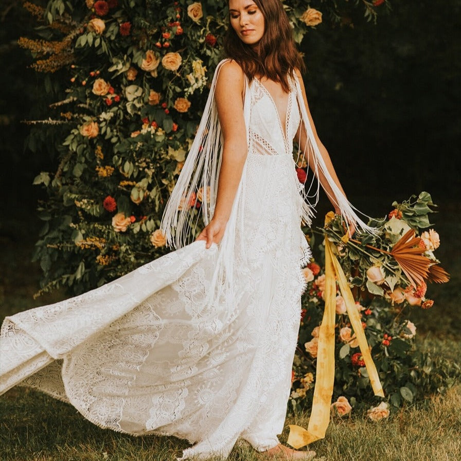 Experience pure elegance and bohemian charm with the Robe Posey. This unique wedding dress features ethereal tassel fringe and a deep V-neck, perfectly embodying the typical style of Rue. Feel like a true boho bride in this beautifully crafted bridal gown.