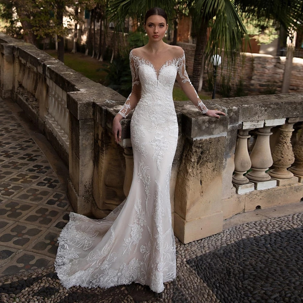 Indulge in the luxury of the Robe Neila. With its elegant lace design, this bridal gown exudes sophistication and chic style. The open back and siren mermaid silhouette add a sexy touch, making you feel like a true siren on your special day. Elevate your bridal look with this exclusive piece.